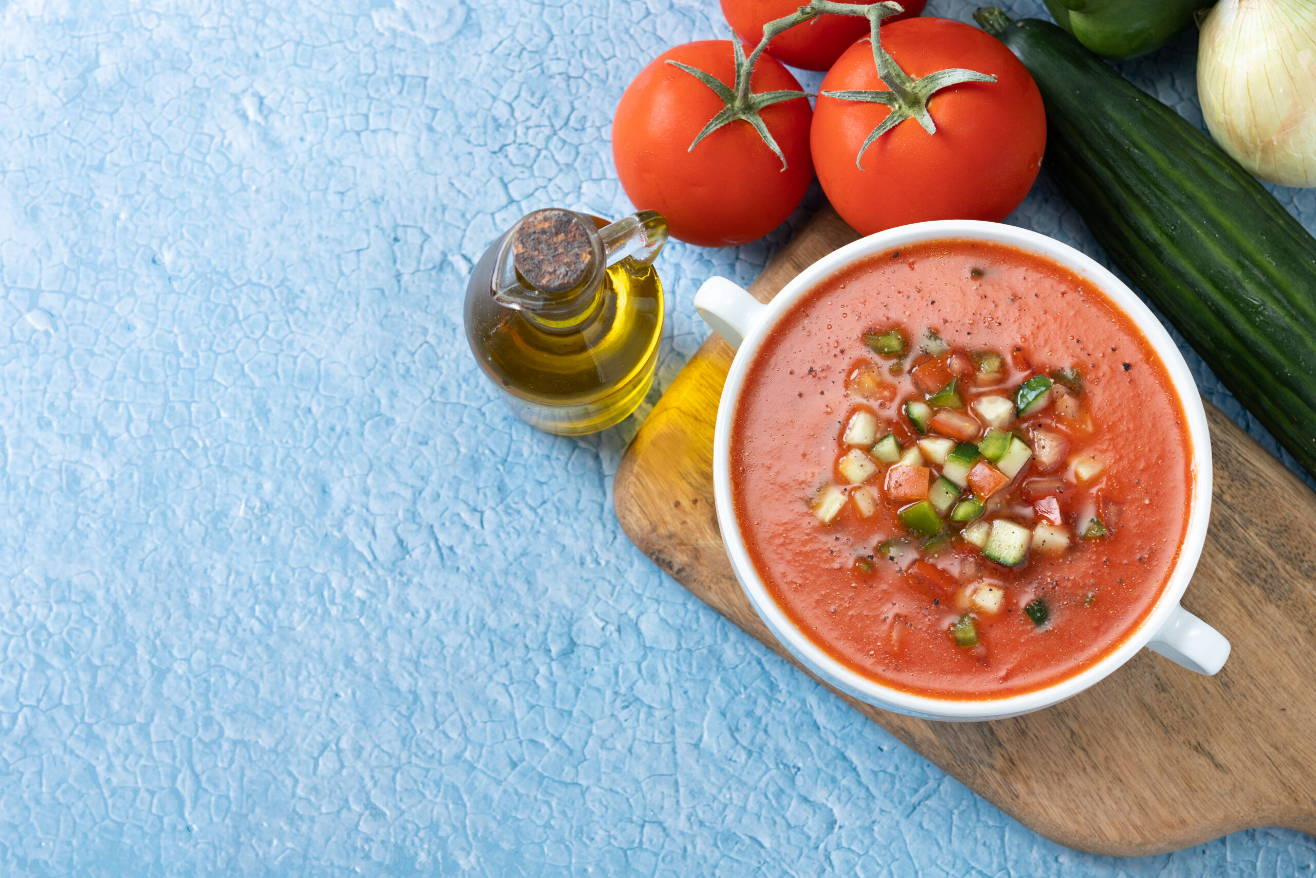 Traditional Spanish gazpacho soup in bowl on blue background